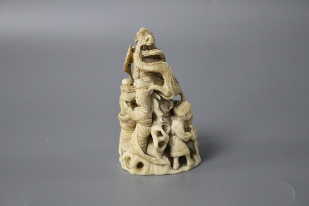 A Japanese Meiji period carved ivory group of a goddess and dragon with attendants, signed to the underside, height 8cm